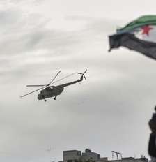 Helicóptero militar lança flores e confetes sobre multidão comemorando os dez anos da vitória de forças rebeldes sobre o exército de Bashar al-Assad em Idlib, Síria, em 28 de março de 2025. Foto: © Ghaith Alsayed / АР / RFI